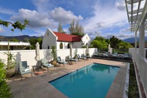 a swimming pool with chairs and a house at Chapter House Boutique Hotel by The Living Journey Collection in Franschhoek