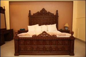 Hotel OR Odyssey Residence في ملتان: سرير خشبي كبير مع وسائد بيضاء في غرفة النوم