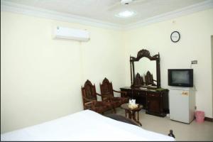 Hotel OR Odyssey Residence في ملتان: غرفة نوم بسرير وتلفزيون ومرآة
