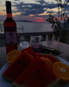 un piatto di frutta su un tavolo con una bottiglia di vino di Guesthouse Villa Paškal a Zaostrog