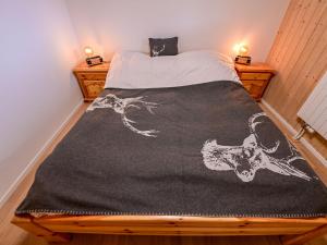 a bed with a black and white blanket on it at Chalet La Paisible by Interhome in Ovronnaz