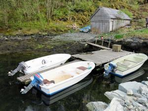 two boats sitting on the water next to a dock at Holiday Home Solbakken - FJS547 by Interhome in Gjølanger