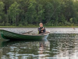 a man in a boat on a lake holding a rod at Holiday Home Sakarinniemi by Interhome in Kortteinen