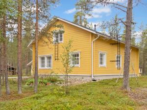 ein gelbes Haus im Wald mit Bäumen in der Unterkunft Holiday Home Jutapirtti by Interhome in Levi