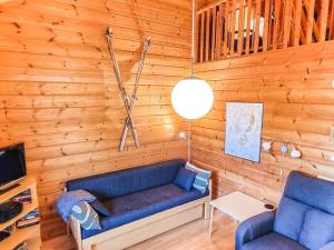 a living room with a blue couch in a wooden wall at Holiday Home Lähikaltio 329 by Interhome in Äkäslompolo