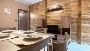 a dining room with a table and a wooden wall at Апартхотел Конниците in Veliko Tŭrnovo