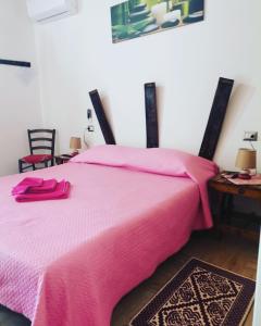 - une chambre avec un lit rose, une table et des chaises dans l'établissement SA DOA, à Baratili San Pietro