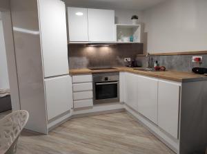 uma cozinha branca com armários brancos e um fogão em Precioso apartamento en una villa con piscina en Cumbre del Sol Moraira Benitachell em Cumbre del Sol
