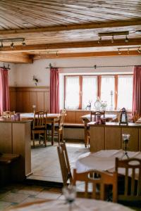 a dining room with tables and chairs and windows at Hotel Vogtareuther-Hof in Vogtareuth