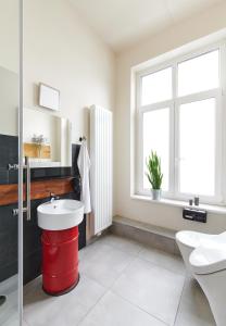 a bathroom with a red trash can and a sink at Old Printing House in Hannover