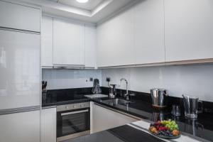 - une cuisine avec des placards blancs et un bol de fruits sur le comptoir dans l'établissement Royal Club By RVHR, Noora Tower, Al Habtoor City, Business Bay, à Dubaï