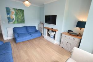 ein Wohnzimmer mit einem blauen Sofa und einem TV in der Unterkunft RedButt House, Freshwater, 3 Bedrooms, WiFi, Garden in Freshwater