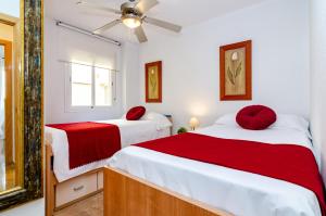 a bedroom with two beds with red pillows on them at WintowinRentals Pool, Sunny side & Free Parking. in Torre de Benagalbón