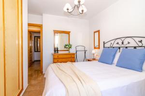 a bedroom with a large white bed with blue pillows at WintowinRentals Pool, Sunny side & Free Parking. in Torre de Benagalbón