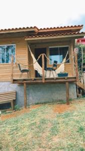 a porch with two chairs and a hammock on a house at Paraíso do Rosa in Praia do Rosa