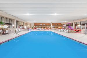 a pool at a hotel with tables and chairs at Ramada by Wyndham Grayling Hotel & Conference Center in Grayling