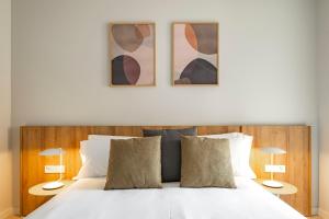 a bed with two pillows and two pictures on the wall at Aspasios Garden Apartments in Barcelona