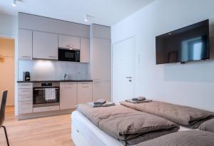 a kitchen with white cabinets and a flat screen tv at HITrental Central Station Apartment in Zürich