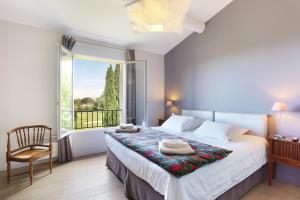 a bedroom with a bed with a window and a chair at Villa Briali Pont Royal in Mallemort