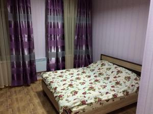 Bett in einem Schlafzimmer mit lila Vorhängen in der Unterkunft ShangHai Hotel in Konotop
