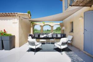 patio z białymi krzesłami i kanapą w obiekcie Villa Briali Pont Royal w mieście Mallemort