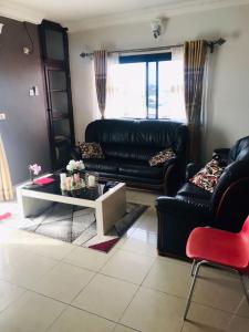 a living room with a black leather couch and a coffee table at Appartements meublés Sorel in Douala