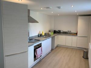 a kitchen with white cabinets and a stove top oven at 29 Malthouse Alnwick Holiday Apartment in Alnwick