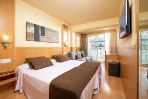 リョレート・デ・マルにあるHotel Guitart Central Park Aqua Resortの大型ベッドとテレビが備わるホテルルームです。
