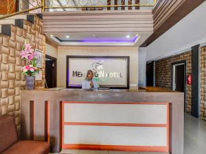 a woman standing at a bar in a lobby at Collection O 90564 Hotel Merangin Syariah in Bangko