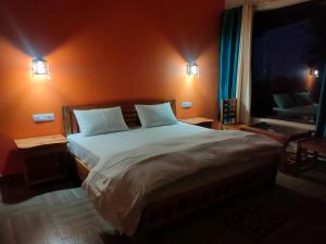 a bedroom with a large bed with two night lights at Kasar wonder hill homestay in Almora