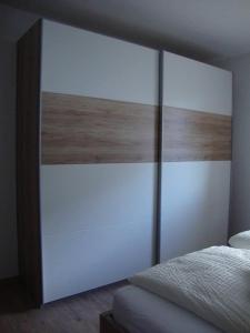 Schlafzimmer mit einem großen Kopfteil aus Weiß und Holz in der Unterkunft Haus am Bühel in Gaschurn