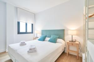1 dormitorio con 1 cama blanca grande con almohadas azules en El Limonar, en Los Barrios