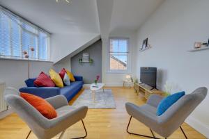 a living room with a blue couch and two chairs at Leamington Spa Warwick Place Apartments in Leamington Spa