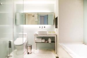 a bathroom with a sink and a toilet and a mirror at Ambience Hotel Taipei in Taipei