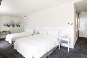 台北的住宿－喜瑞飯店，配有白色墙壁的酒店客房内的两张床