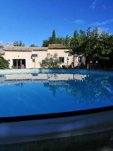 Blick auf einen Pool mit einem Haus im Hintergrund in der Unterkunft LE CABANON in Crillon-le-Brave