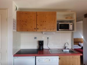 uma cozinha com um balcão vermelho e um lavatório em CHAMROUSSE-SPORT&DETENTE appartement 6 couchages avec superbe vue em Chamrousse