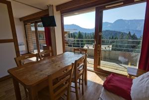 Un comedor con una mesa y un gran ventanal. en CHAMROUSSE-SPORT&DETENTE appartement 6 couchages avec superbe vue, en Chamrousse