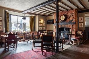 a dining room with a fireplace and tables and chairs at The Hoste and The Vine House Hotels in Burnham Market