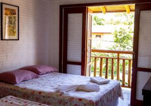 1 dormitorio con 1 cama y balcón con ventana en Pousada Território da Paz, en Garopaba