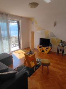 uma sala de estar com um sofá e uma televisão em Apartman Lamia s pogledom na more em Rijeka