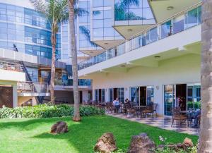 um edifício com palmeiras e pessoas sentadas num pátio em The Boma Nairobi em Nairobi