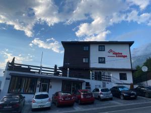 a building with cars parked in front of it at Alpine Lounge Kazbegi in Stepantsminda