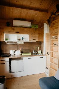 - une cuisine avec des placards blancs et des murs en bois dans l'établissement KORCAL faházak, à Koroncó