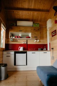 a kitchen with white cabinets and wooden walls at KORCAL faházak in Koroncó