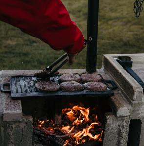 une personne prépare des hamburgers sur un grill dans l'établissement KORCAL faházak, à Koroncó