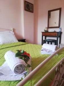 1 dormitorio con 1 cama verde, toallas y espejo en Elli Rooms en Patitiri