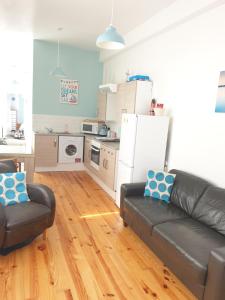 a living room with a black couch and a kitchen at Cosy seaside apartment in Woodhorn