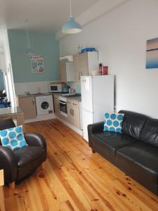a living room with a black leather couch and a kitchen at Cosy seaside apartment in Woodhorn