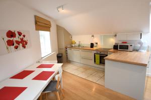 uma cozinha com armários brancos e uma mesa vermelha e branca em The Coach House Studio Apartment em Leamington Spa